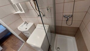 A small bathroom with a toilet, sink, and shower. - Vasile Apartment studio  (Bucharest)