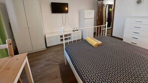 A bedroom with a bed, a desk, a TV, a wardrobe, and a dresser. - Vasile Apartment studio  (Bucharest)