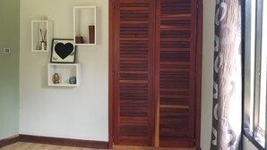 Ein Zimmer mit Holztür, weißen Regalen mit Dekoration und einem Fenster mit gemusterten Vorhängen.