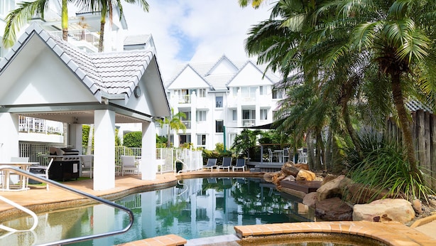 Une piscine avec un jacuzzi, entourée de chaises longues et dotée d’un patio couvert.