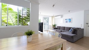 Un salon moderne avec un canapé gris, une table à manger en bois et une plante en pot.