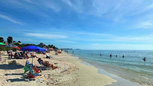 A beach with people swimming and sunbathing, umbrellas, and beach chairs. - Seashell Serenity Beach Escape - Just 5 minutes from Lovely Bonita Beach Park! (Bonita Springs)