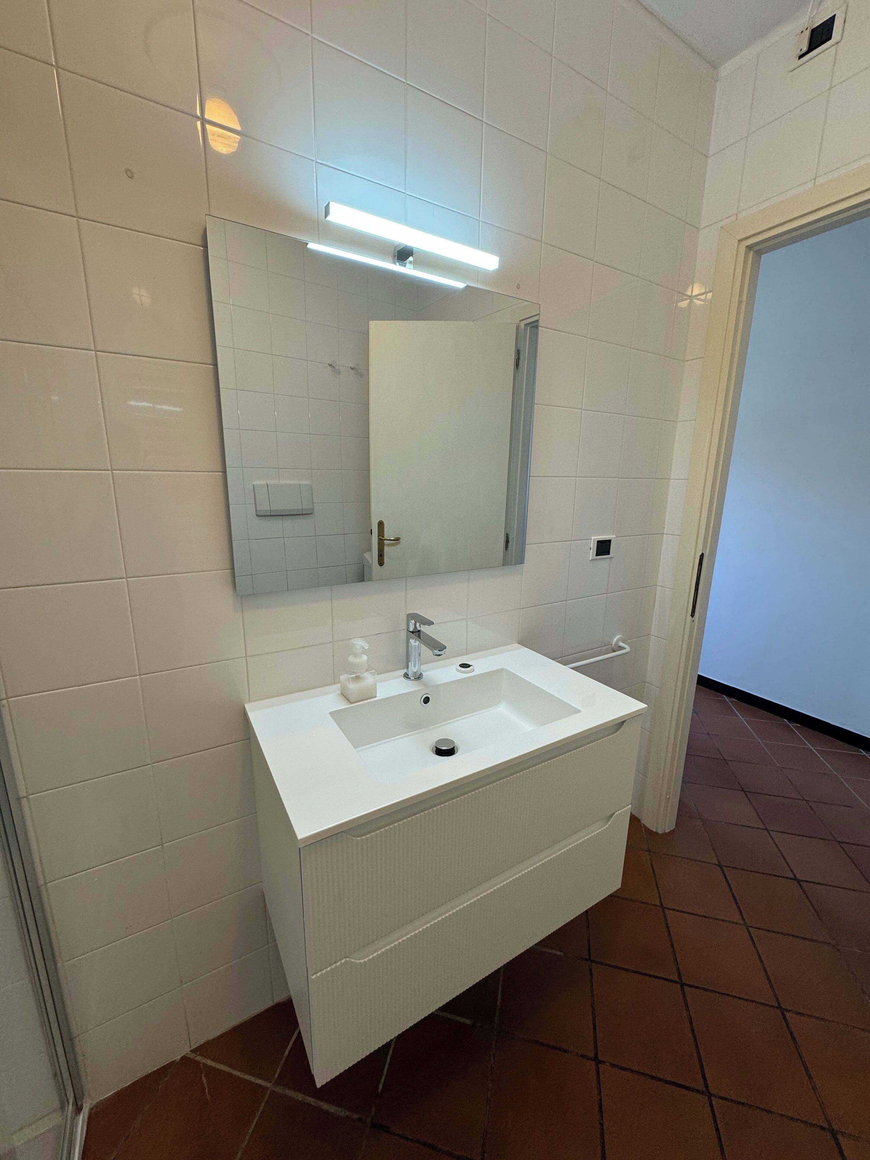 A bathroom with a white sink, mirror, and overhead lighting.