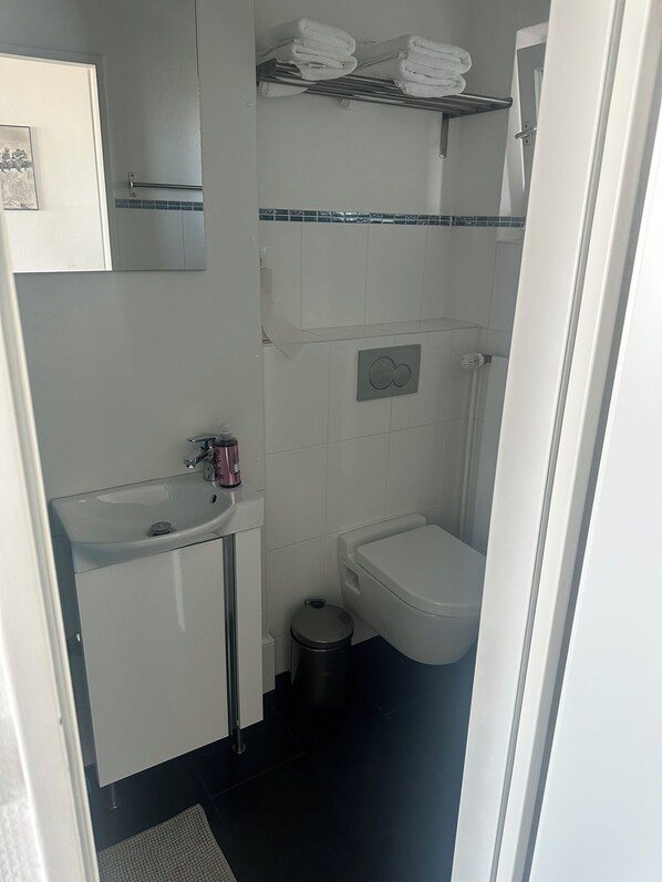 Un baño pequeño y limpio con lavamanos, inodoro y un perchero para toallas.