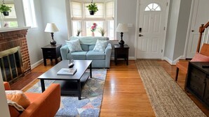 A living room with a fireplace, a sofa, a coffee table, and a door.