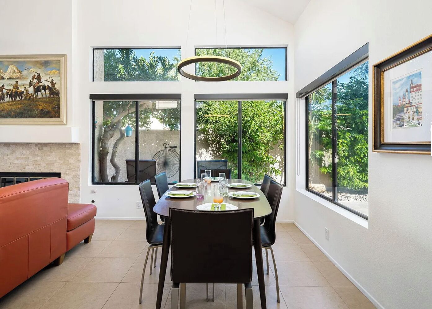 Un espace repas moderne, doté d’une grande table, de chaises et offrant une vue sur la verdure environnante.