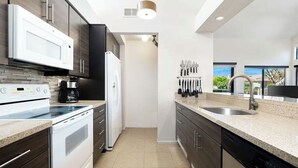 Una cocina moderna con armarios de madera oscura, electrodomésticos blancos y encimera de granito.