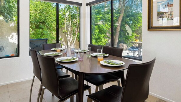 Un comedor con una mesa redonda, sillas negras y ventanas amplias que dan a zonas verdes.