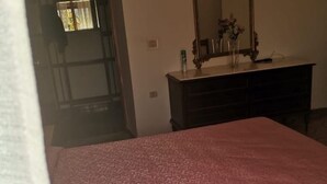 A room with a patterned bedspread, a dresser with a mirror, and a vase with flowers. - 🏡 Holiday Apartment in Policastro Bussentino (Policastro Bussentino)