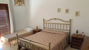 A bedroom with a double bed, a single bed, a nightstand, a dresser, and a chandelier. - 🏖️ Cozy Holiday Apartment 300m from the Sea - Policastro Bussentino #1 (Policastro Bussentino)
