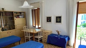 A room with two beds, a desk, and a chair. There is a window with curtains, a bookshelf, and two framed pictures on the wall. - 🏖️ Cozy Holiday Apartment 300m from the Sea - Policastro Bussentino #1 (Policastro Bussentino)