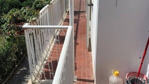 A narrow outdoor corridor with a white metal railing, a red-tiled pathway, and a white wall. - 🏖️ Cozy Holiday Apartment 300m from the Sea - Policastro Bussentino #1 (Policastro Bussentino)