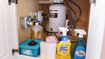 A storage cabinet with a water filtration system, a dishwasher pod, and cleaning supplies.