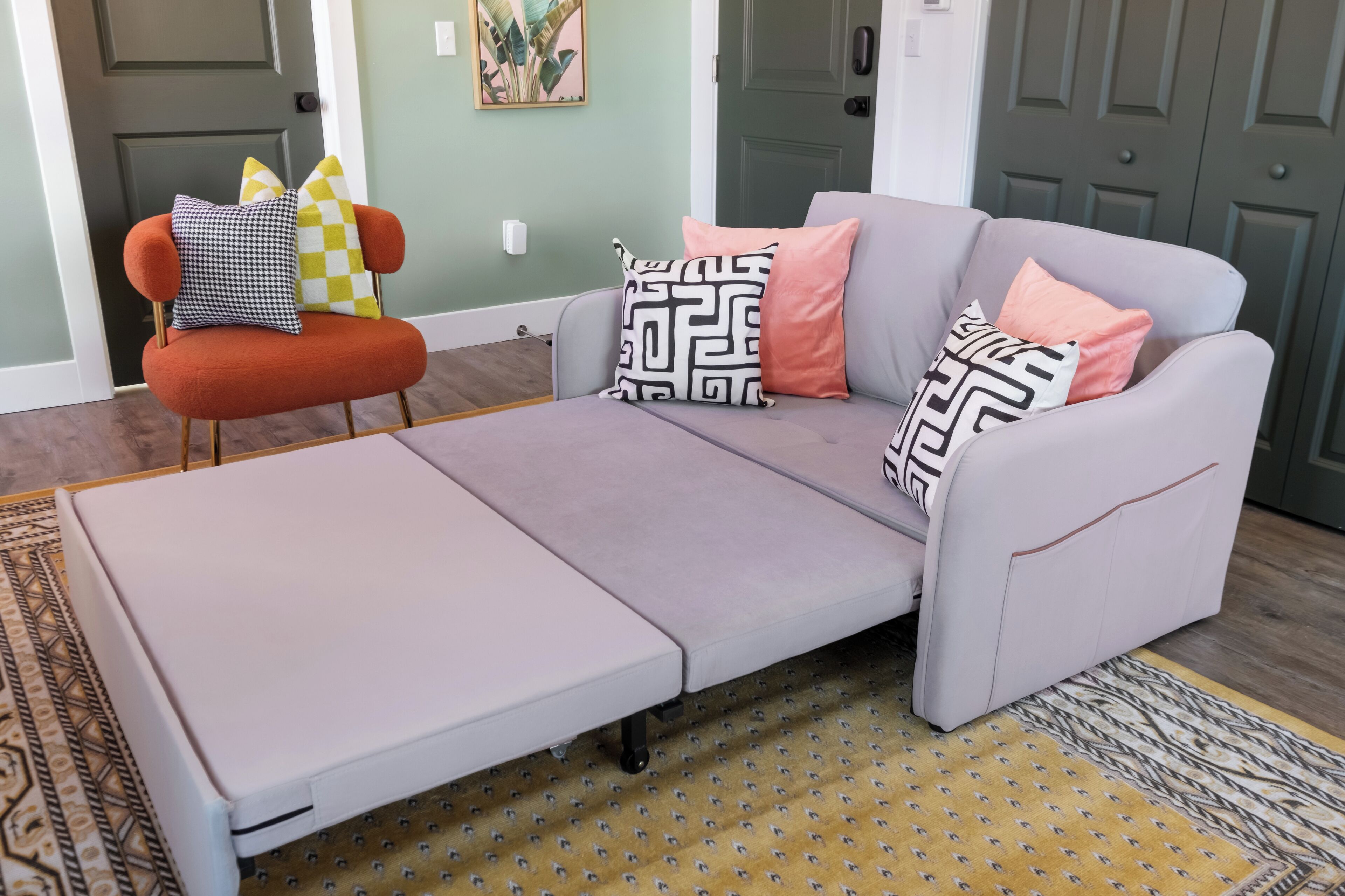 Un salón moderno con un sofá gris, un sillón naranja y cojines estampados.