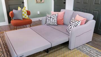 Un salón moderno con un sofá gris, un sillón naranja y cojines estampados.
