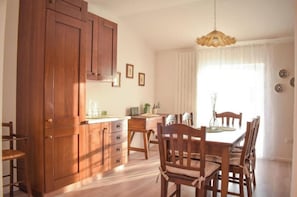 A wooden dining table with chairs, a wooden cabinet, and a hanging light fixture.