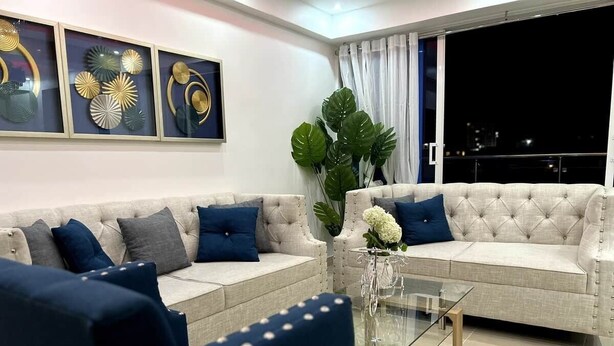 A modern living room with a sofa, armchairs, and a glass coffee table. - Luna by Suarez Properties | Jacuzzi, & BBQ (Santo Domingo Este)