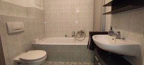 A bathroom with a toilet, bathtub, and sink. - Vacation apartment Cottbuser City II (Cottbus)