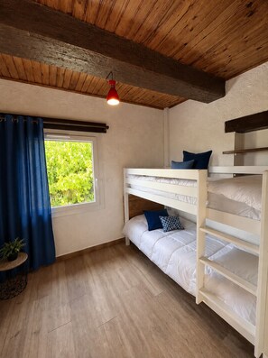 Une pièce avec des lits superposés, une fenêtre avec des rideaux, une lampe rouge suspendue et un plafond en bois.