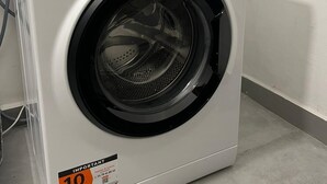 A white Hotpoint washing machine with a control panel, a digital display, and a "10" discount sticker.