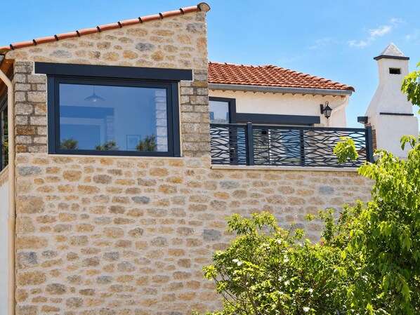 A stone building with a large window and a metal fence.
