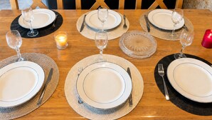 A dining table set for four with plates, cutlery, and wine glasses.