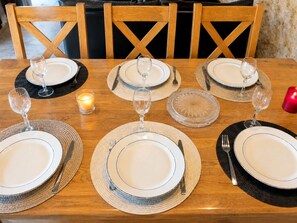 A dining table set for four with plates, cutlery, and wine glasses. - Le Cocon de Soie, charming gîte between Uzès, Nîmes and Anduze, in the Gard . (Saint-Jean-de-Ceyrargues)