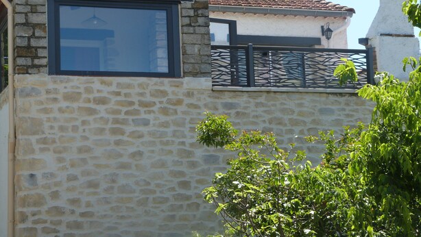 A stone building with a window and a metal gate.