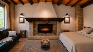 Una habitación acogedora con chimenea, cama, sofá y una mesita.