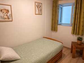 A small, single-bed room with a green patterned bedspread, a wooden headboard, a small bedside table with a plant, and two framed animal pictures on the wall. - Le Cocon de Soie, charming gîte between Uzès, Nîmes and Anduze, in the Gard . (Saint-Jean-de-Ceyrargues)