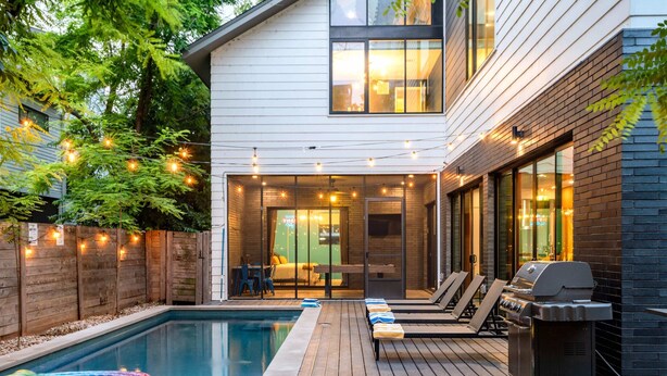 Ein Garten mit Swimmingpool, Grill und einer Terrasse mit Liegestühlen.