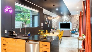 Eine moderne Küche mit schwarzem Arbeitsplatz, Holzschränken und einer Neonreklame.