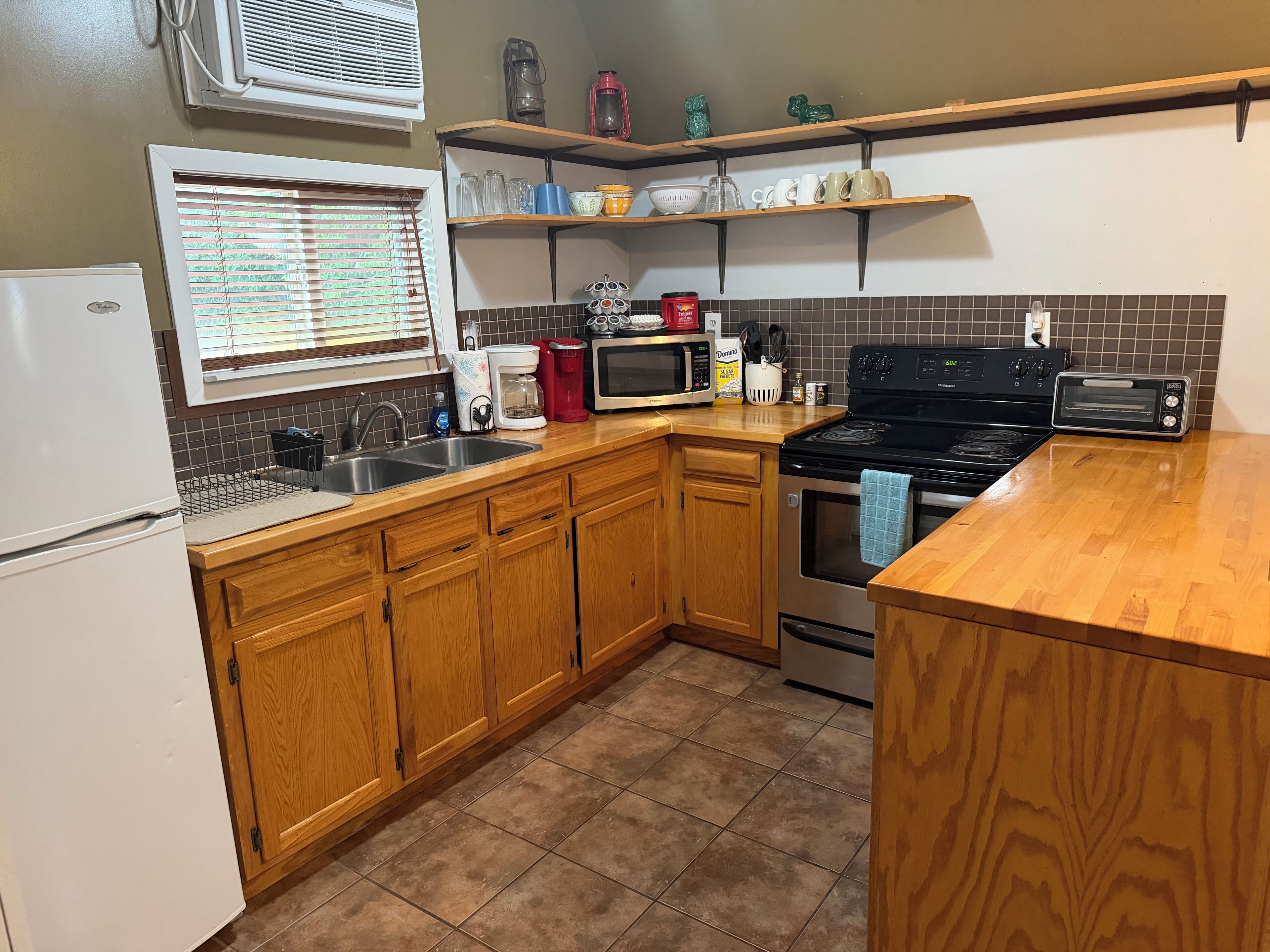 A kitchen with wooden cabinets, a refrigerator, a microwave, a stove, and a toaster.