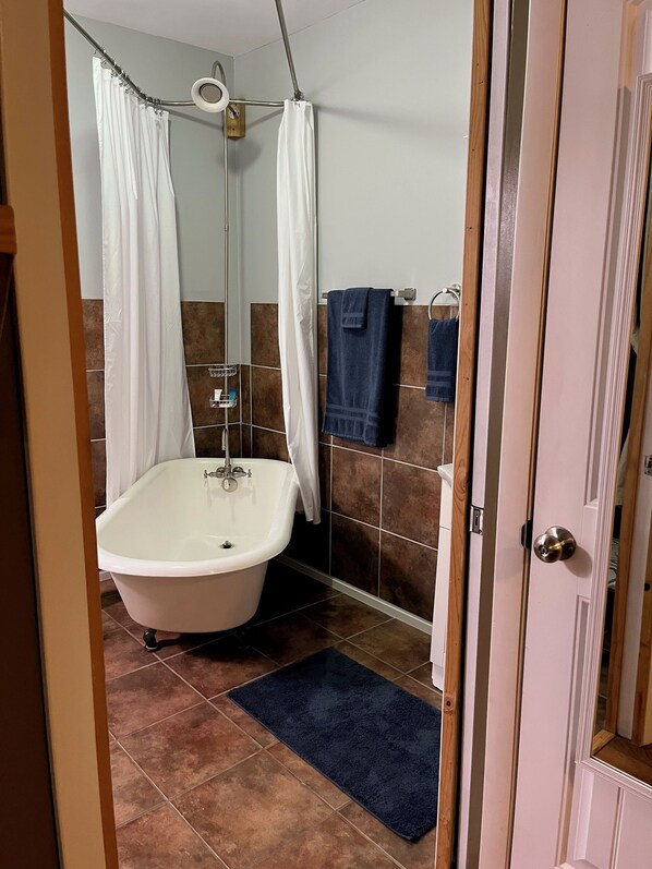 Ein Badezimmer mit einer freistehenden Badewanne, einer Duschvorhang und einem Handtuchhalter mit Handtüchern.