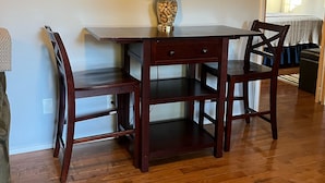 Un comedor con una mesa y sillas de madera, una lámpara con base de corcho y un ventilador de techo.