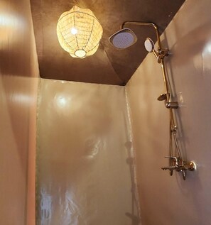 Une douche équipée d’un pommeau de douche à main et d’un robinet fixé au mur.