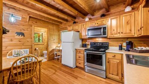 A wooden cabin kitchen with a refrigerator, stove, microwave, and wooden cabinets.