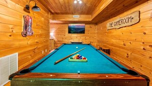 A pool table in a wooden room with a sign reading "THE GAMEROOM".