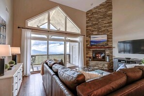 A spacious living room with a large window, a fireplace, and a television.