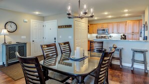 A dining area with a glass table, wooden chairs, and a chandelier. - Updated condo at 5100' with breathtaking views! (Sugar Mountain)