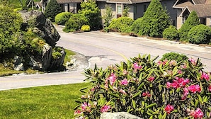 A residential area with houses, a driveway, and a large rock with pink flowers. - Updated condo at 5100' with breathtaking views! (Sugar Mountain)