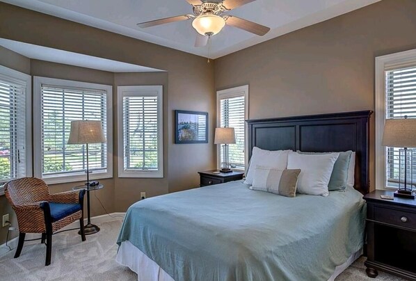 A bedroom with a bed, two nightstands, a chair, and a ceiling fan.