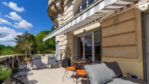 Una terraza en la azotea con mobiliario exterior, una mesa de comedor y vistas del paisaje circundante.