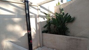 A narrow outdoor corridor with a wooden deck, a black pole, and a potted plant. - Villa les volets bleus - swimming pool - near the calanques of Cassis (Roquefort-la-Bédoule)