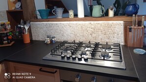 A kitchen with a gas stove, wooden cabinets, and a variety of kitchenware on the countertop. - Villa les volets bleus - swimming pool - near the calanques of Cassis (Roquefort-la-Bédoule)