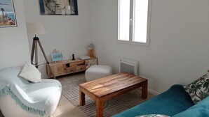 A living room with a sofa, a wooden coffee table, a lamp, a side table, and a window. - Villa les volets bleus - swimming pool - near the calanques of Cassis (Roquefort-la-Bédoule)