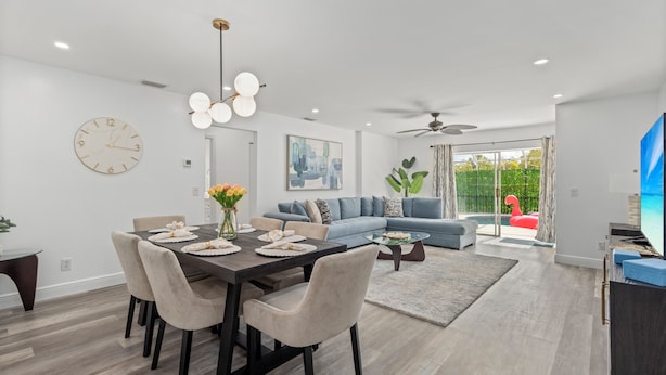 A modern living room with a dining area, a large sofa, and a television.