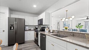 A modern kitchen with white cabinets, stainless steel appliances, a granite countertop, and a built-in oven.