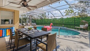 A covered outdoor area with a pool, seating, and a ceiling fan.