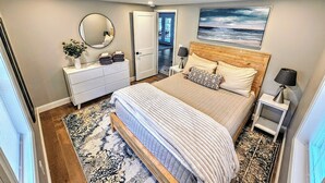 Une chambre à coucher avec un lit, des tables de chevet, une commode, un miroir et un tableau au mur.